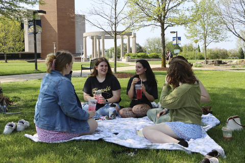 five female students sitting on the quad