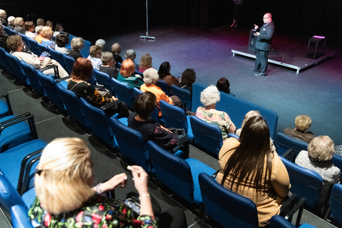 a man talks to a group of women inside the UIS Studio Theatre