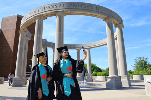 graduate taking pic in front of colonnade