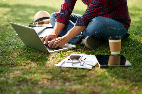 Student creating a learning portfolio on a laptop outdoors at UIS