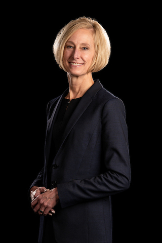 Chancellor Gooch's formal portrait, hand clasped, standing in front of a dark background.