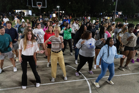 Chancellor dances with students outside at an evening event
