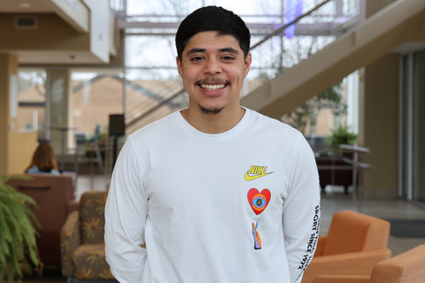 UIS student smiles inside a campus building with seating and staircases in the background.