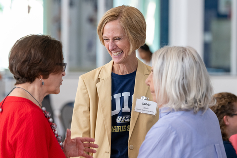 Three women engaging in conversation, smiling warmly.