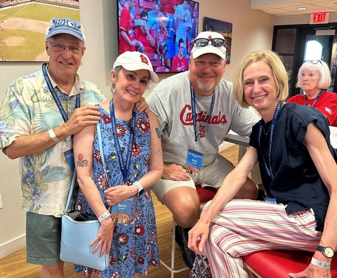 Four friends smiling together indoors with sports decor in the background.