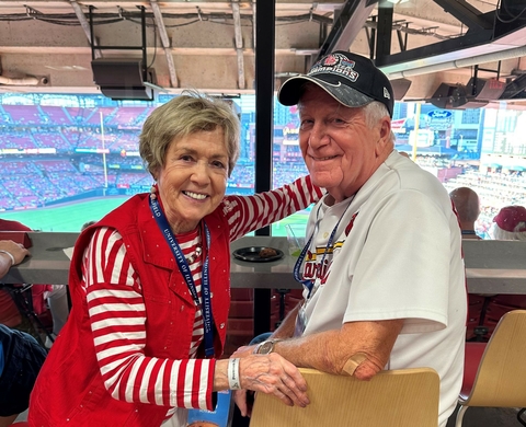 couple smiling at a baseball game, indoor stadium in the background.