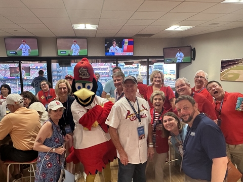 Group of people with Fredbird, smiling indoors at a Cardinals game