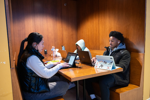 Three people on computers at a table together.