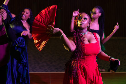 Woman dressed in red holds a red fan while dancing at the Ebony Ball.