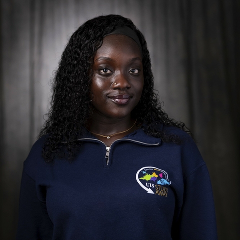 Student with black curly hair wearing a blue sweatshirt
