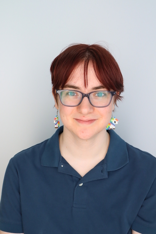 student posed in front of light blue background with navy blue shirt.
