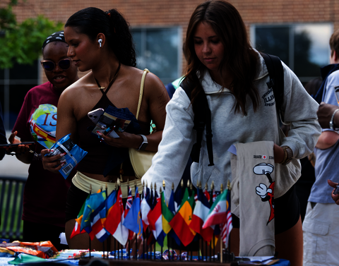 Two young women stopping at a table full of flags.