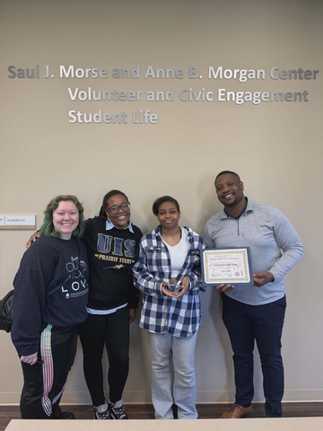 Dr. J presenting Student of the Month Award to Kailynn Jackson-Green with two other staff members.