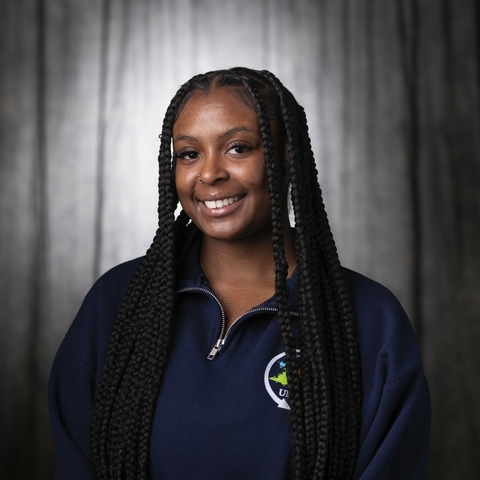 Smiling student with long dark braids wearing a blue Study Away sweatshirt