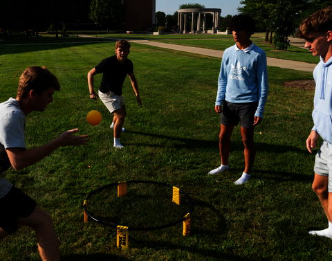 Four males playing spikeball.