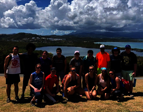 A group of students smiling in front of an edge of a cliff.