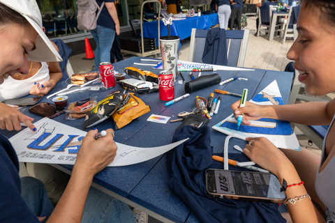 People crafting signs at a table with markers and drinks.