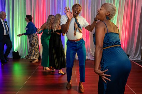 People dancing joyfully with colorful lights in the background.