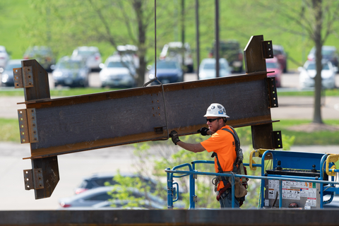 Construction crew member installing support beam to Library Commons