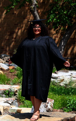 A women posing in a black cap and gown.
