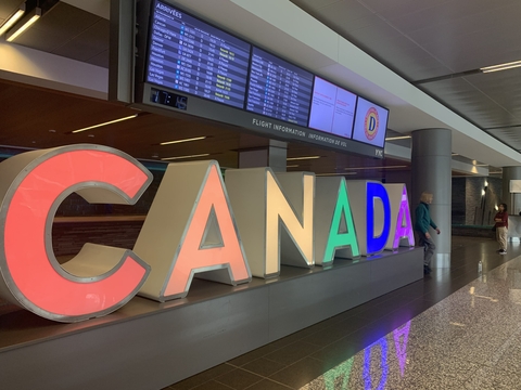 Airport arrivals, large colorful Canada welcome sign 