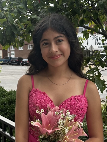 student posed in front of a tree holding a flower.