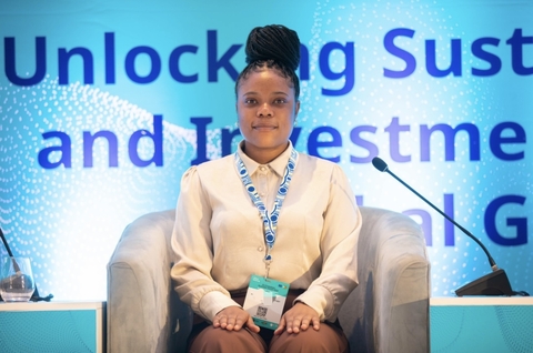 student posed in a seat in front of words from a presentation.