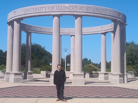 student posed in front of the UIS Colonnade