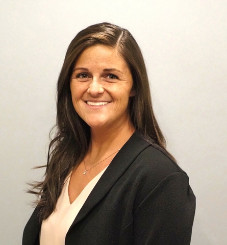Professional headshot of Brooke Valenti Jouett smiling against a light gray background, wearing a black blazer over a white top.