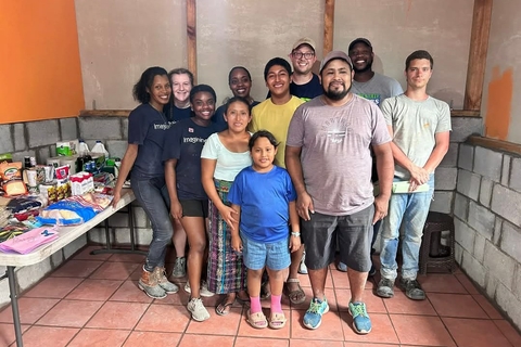 UIS students and a local family gather inside a finished home with a table full of donated supplies.