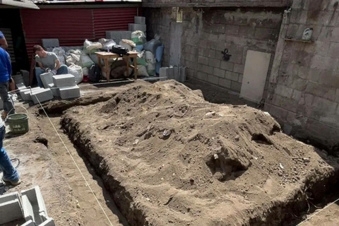 A home construction site shows dirt trenches and stacked blocks during early building stages.