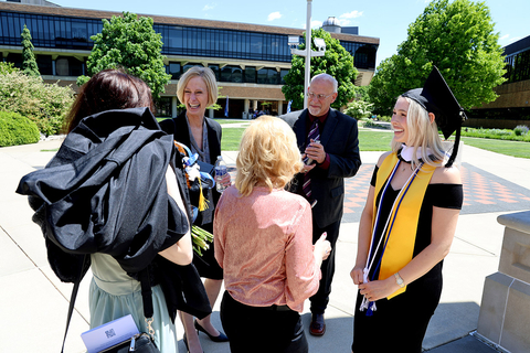 the chancellor outside talking to a graduate and their family by the colonnade