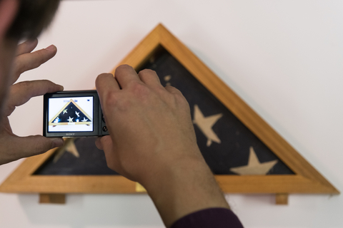 Close up of someone taking a picture of a folded flag