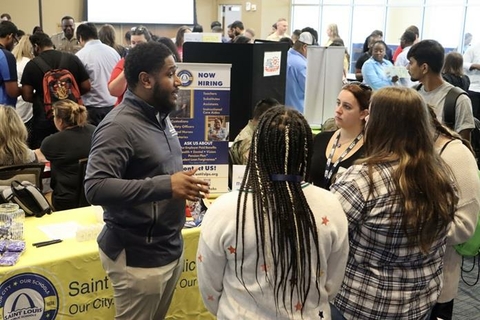 students listening to someone at a career fair booth