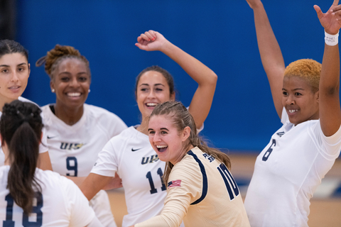 A group of volleyball players cheer.