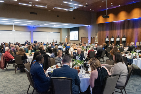 A group of people sit at tables in the Student Union Ballroom. 