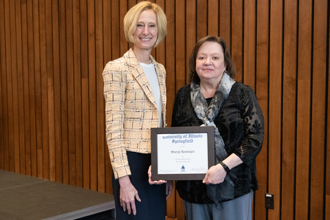 Chancellor Gooch and Sheryl Reminger pose for photo with Sheryl's framed certificate for the 2025 Faculty Excellence Award.
