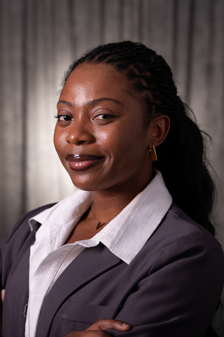 Professional headshot of Victoria wearing a white button-down shirt and gray blazer, smiling with a neutral background.