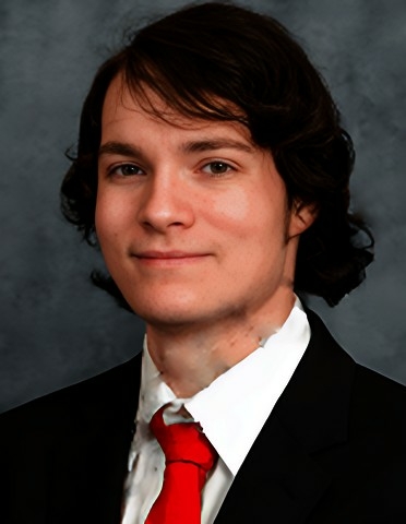 Professional headshot of Colten wearing a white button-down shirt, black blazer, and red tie with a neutral background.
