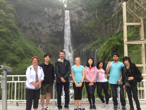 professors and students posing in front of a waterfall in Japan