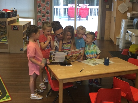 children gathered around caretaker for story time