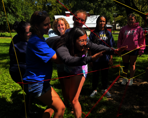 UIS students helping each other through a challenge course obstacle
