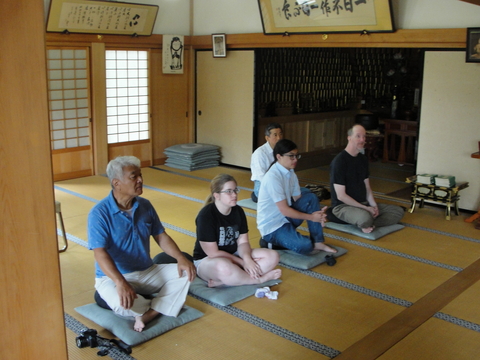 professors and students sitting on mats in a tea house