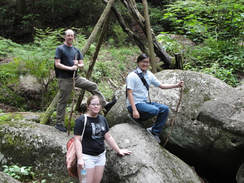 professor and students posing outside in Japan on large boulders