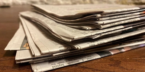 A stack of newspapers on a desk.