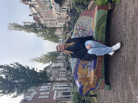 Julie Nash sitting on a bench in a picturesque street.