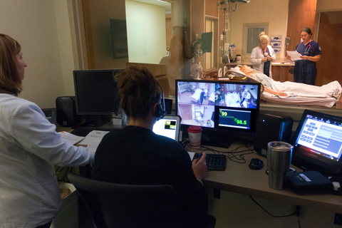 Professors monitor students participating in the nursing simulation lab. 