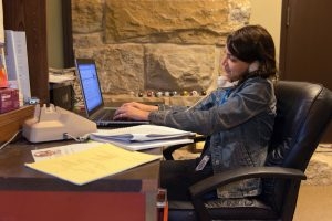 student sitting at desk on laptop while on the phone