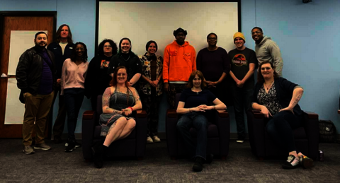Students and staff standing up behind 3 guests speakers sitting down.
