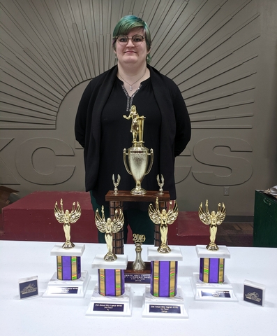 Team Member Sarah Burris posing with Speech and Debate trophies won